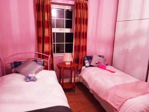 two twin beds in a room with pink walls at Hardwood Hall in Kinnegad