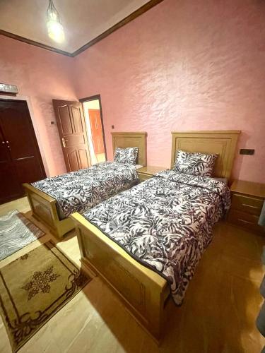 2 camas en una habitación con paredes rosas en SAHARA APPARTEMENTS, en Merzouga