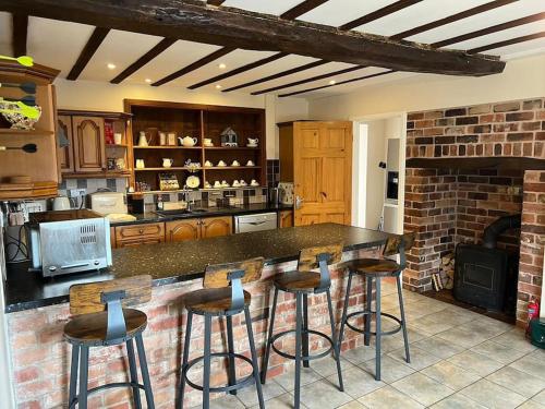 a kitchen with a counter and bar stools in it at Upper Caerfaelog Farmhouse in Llanbister