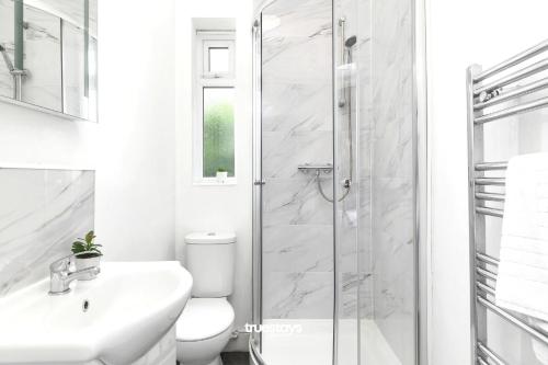 a white bathroom with a shower and a toilet at NEW Oakhill House by Truestays - 5 Bedroom House in Stoke-on-Trent in Trent Vale