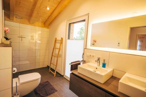 a bathroom with a sink and a toilet and a mirror at Haus Plattenbichlstraße - Ferienhäuser Alpenglück in Oberstdorf