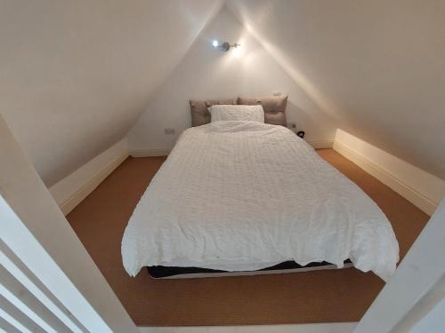 a bedroom with a white bed in a attic at Epsom Road studio flat in Croydon