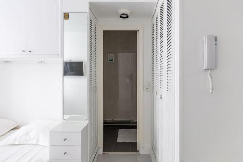 - une chambre blanche avec un lit blanc et un miroir dans l'établissement Le LONGCHAMP Paris 16 ème, New and perfectly located apartment, à Paris