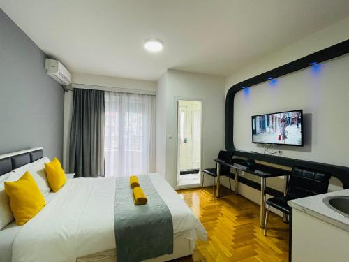 1 dormitorio con cama con almohadas amarillas y escritorio en Front Beach Exclusive Apartments en Struga