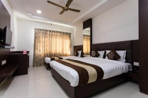 Hotel Ramida Suites At Delhi Airport في نيودلهي: غرفة نوم بسرير كبير ومروحة سقف