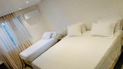 a white bed in a room with a window at Hotel Vista Caribe Azúa in Azua de Compostela