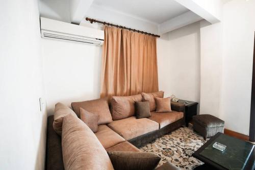 ein Wohnzimmer mit einem braunen Sofa in einem Zimmer in der Unterkunft Amazing Flat 9 mins to Airport at Heliopolis in Kairo