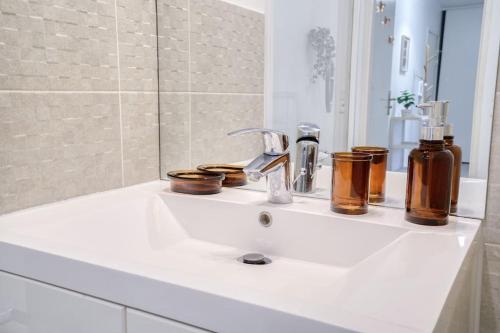 a bathroom with a sink with bottles and a mirror at Le Colorful Bohème - proche Paris in Rosny-sous-Bois