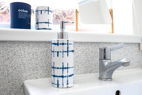 a bathroom sink with a blue and white toothbrush holder at Fielding House by Truestays - NEW 3 Bedroom House in Stoke-on-Trent in Stoke on Trent