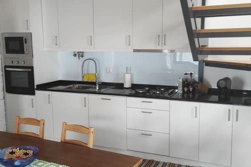 a white kitchen with a sink and a stove at Da Silva house in Seia