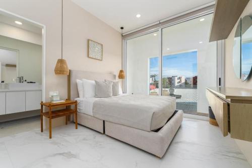 a white bedroom with a bed and a large window at New 3BR condo with exceptional location with pool in Cabo San Lucas