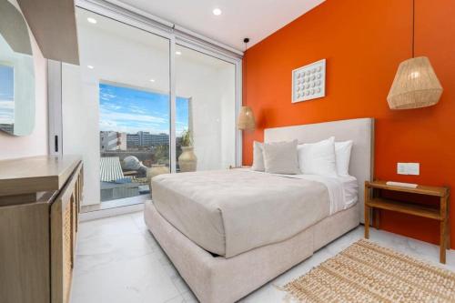 a bedroom with an orange wall with a bed and a window at New 3BR condo with exceptional location with pool in Cabo San Lucas