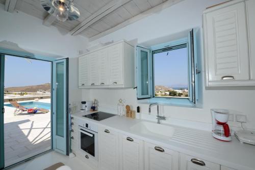 a kitchen with white cabinets and a view of the ocean at Villa Danelina by Whitelist Mykonos in Ornos