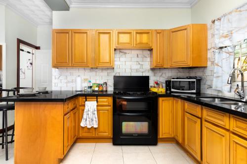 una cocina con armarios de madera y electrodomésticos negros en Cozy, upscale apartment centrally located in Kgn 6, en Kingston