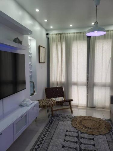 a living room with a flat screen tv and a chair at Chalet The Palm Retreat Buye, Playa Buyé in El Cerro