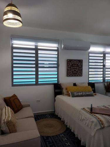 a bedroom with a bed and a couch and windows at Chalet The Palm Retreat Buye, Playa Buyé in El Cerro