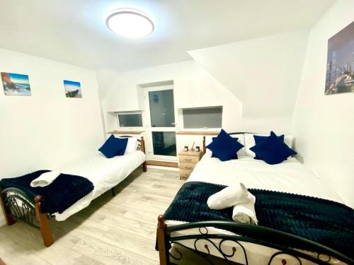 two beds in a room with blue pillows at Cozy One Bedroom Apartment With Free Car Park In London in London