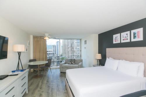 a hotel room with a bed and a desk and a table at Ilikai Marina 1781 City View Studio in Honolulu