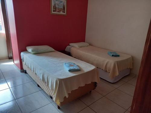 twee bedden in een kamer met rode muren bij Ap duplo econômico, com banheiro, sem café ou TV no Espaço Verona in Fazenda Rio Grande