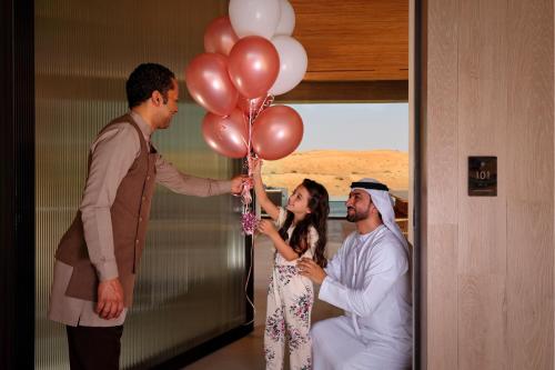 a man giving a woman a bunch of balloons at The Ritz-Carlton Ras Al Khaimah, Al Wadi Desert in Ras al Khaimah
