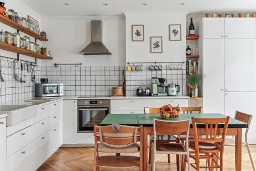 una cocina con mesa y sillas y una cocina con armarios blancos. en PARIS 19eme - ADIDAS ARENA - LA VILLETTE - LES BUTTES CHAUMONTS, en París