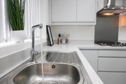 a kitchen with a stainless steel sink and white cabinets at Central Location Liverpool, Modern Home, 4 BR, Sleeps 9, Free Parking in Liverpool