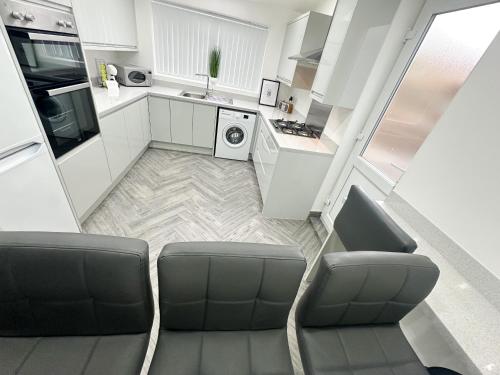 a kitchen with white cabinets and a couch in a room at Central Location Liverpool, Modern Home, 4 BR, Sleeps 9, Free Parking in Liverpool
