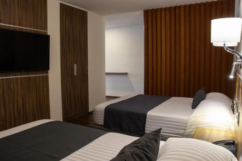 a hotel room with two beds and a flat screen tv at Estanza Hotel & Suites in Morelia