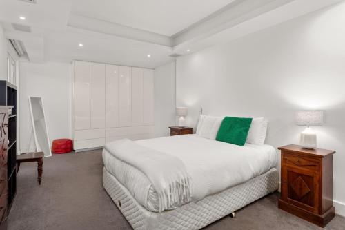 a white bedroom with a large bed and a table at Marlin in Melbourne
