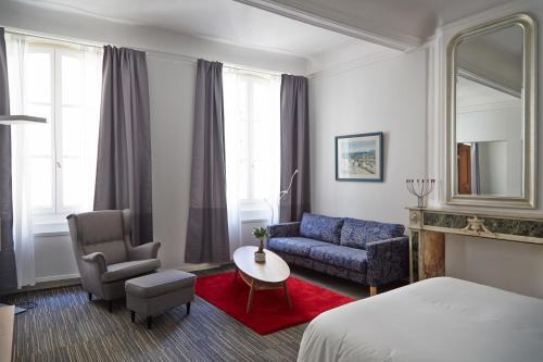 a hotel room with a bed and a couch and a table at La Résidence Arles Centre in Arles