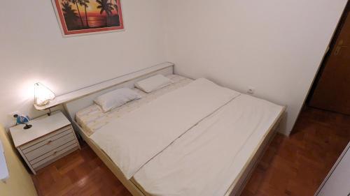 um pequeno quarto com uma cama branca e uma mesa de cabeceira em Apartman PRESSTIGE em Smederevska Palanka