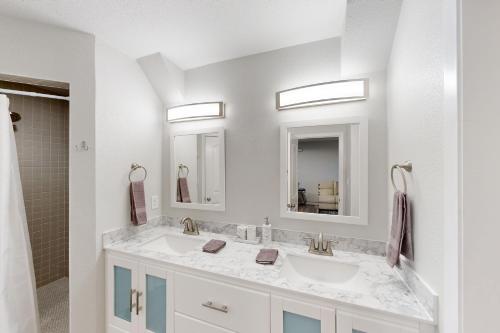 a white bathroom with two sinks and two mirrors at Denton Place Studio in Denton