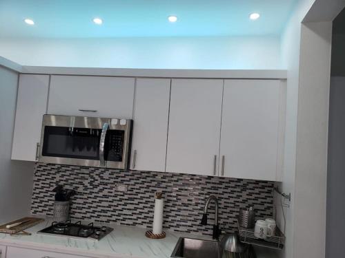 a kitchen with white cabinets and a microwave at The Palm Retreat Buye, Playa Buyé in El Cerro