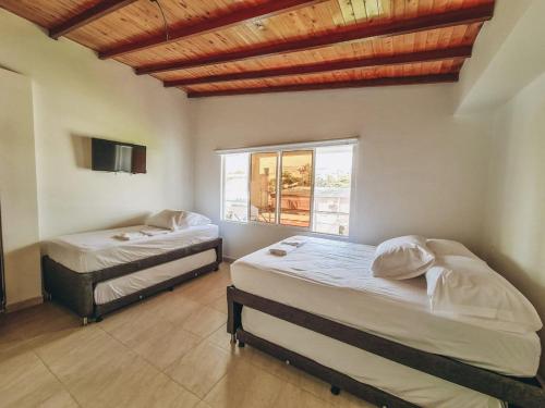 een slaapkamer met 2 bedden en een raam bij Hacienda Nápoles y Santorini Agradable y Fresco Apto in Doradal