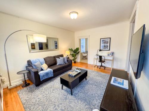 a living room with a couch and a table at Sun-filled 1bed, Corner Unit W Pool In Com Ave in Boston