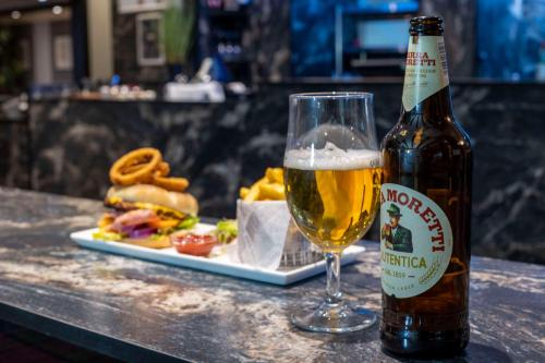 a bottle of beer next to a plate of food at Best Western Manor Hotel in Gravesend