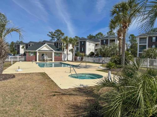a home with a swimming pool and palm trees at 4 Mi to Ocean Breezy Golf Condo in Myrtle Beach! in Myrtle Beach