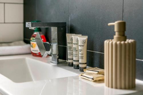 - un lavabo avec une bouteille de savon et un miroir dans l'établissement Tranquil 3-Bedroom Retreat in Narrabundah, à Narrabundah