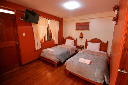 a bedroom with two beds and a flat screen tv at El Chasqui in Ollantaytambo