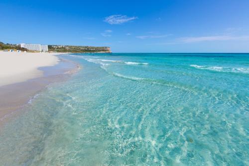 una spiaggia con l'oceano e l'acqua di Apartamento colibrí ad Alaior