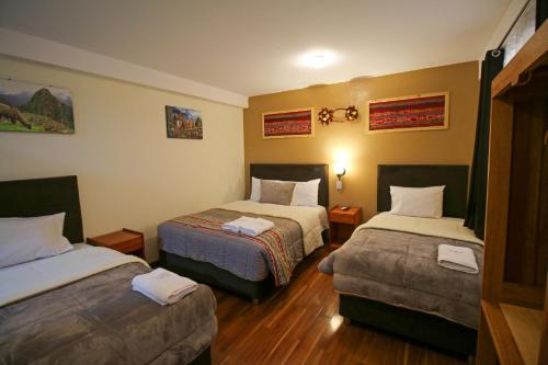 Habitación de hotel con 2 camas y 2 reposapiés en El Chasqui, en Ollantaytambo