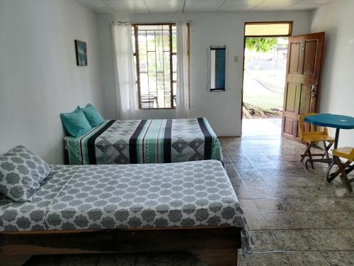 a bedroom with two beds and a table and a door at rooms megi terminal in Cahuita