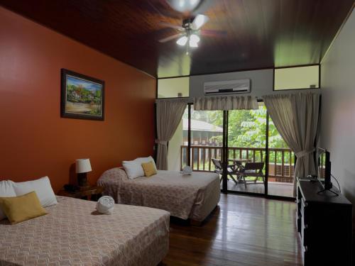 a hotel room with two beds and a balcony at Hotel El Bambu in Sarapiquí