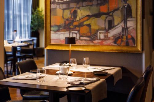 a table in a restaurant with a painting on the wall at Palace Hotel Tallinn, a member of Radisson Individuals in Tallinn