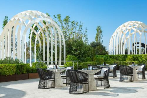a group of tables and chairs in a garden with white arches at Baku Marriott Hotel Boulevard in Baku