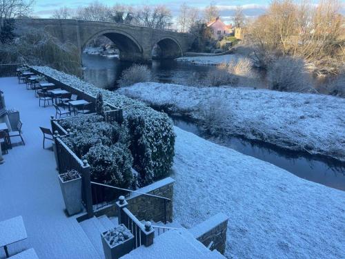 a row of tables and chairs next to a river in the snow at The George - Sure Hotel Collection by Best Western in Darlington