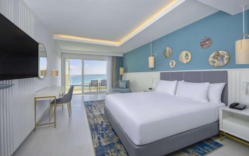 莫纳斯提尔Hilton Skanes Monastir Beach Resort的一间卧室，配有一张床、一张书桌和一台电视