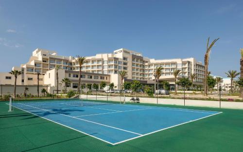 a tennis court in front of a large building at Hilton Skanes Monastir Beach Resort in Monastir