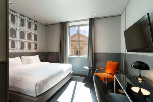 a bedroom with a bed and a tv and a chair at Radisson Collection Hotel, Roma Antica in Rome
