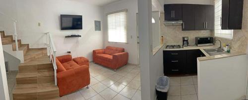 uma cozinha com 2 cadeiras laranja e uma cozinha com uma escada em Apartamentos Tampico-Altamira 